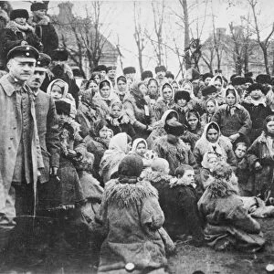 Crowd, possibly of Jewish refugees in the open air in Russia. One of the three uniformed