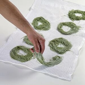 Fresh spinach linguine nests being laid out on kitchen towel, close-up