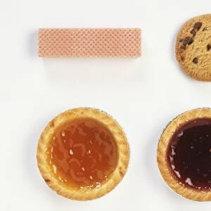 Two jam tarts, chocolate chip cookie, pink wafer, close up from above