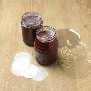 Jars of raspberry jam with waxed paper discs and cellophane covers, close-up
