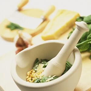 Pine nuts, grated parmesan cheese and green basil leaves in stone pestle with mortar, elevated view