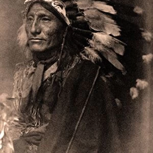 Portrait of Native American man in robe and feather headdress, 1902. Photograph by