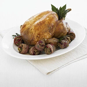 Roast turkey, served with bacon rashers stuffed with cranberries and pistachios, with a garnish of fresh herbs, close-up