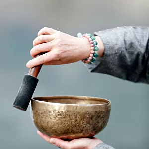 Tibetan bowl is used in sound therapy, meditation and yoga. Woman practicing a singing bowl for sound therapy in atmosphere for healing, meditation and relax. France