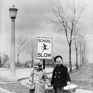 Boy and girl walking to school, about cross street by slow school sign