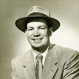 Businessman wearing fedora hat, smiling, (B&W), portrait