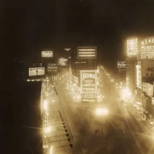 circa 1920: High-angle view of illuminated marquees in Times Square at night