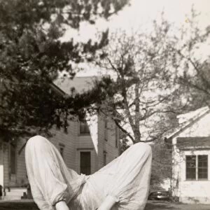 Flexible Woman in a Garden Bending Her Legs Above Her Head