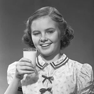 Girl (12-13) posing with glass of milk, (B&W), portrait