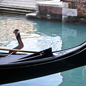 Front of a gondola in a canal with turquoise water