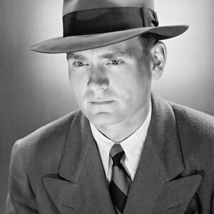 Man in Fedora hat in studio, (B&W), close-up, portrait