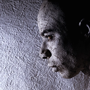 Man wearing face paint, near textured wall, close-up