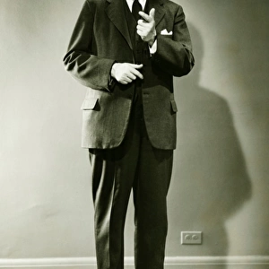 Mature man pointing in studio, (B&W), portrait