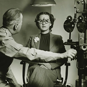 Optician examining patients eyes, (B&W)