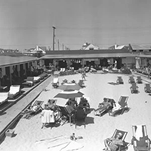 People relaxing by outdoors swimming pool, (B&W), elevated view