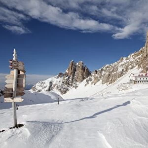Signpost, Tierser Alplhutte mountain cabin and Rosszahne peaks in winter, Seiser Alm alp, Province of South Tyrol, Italy