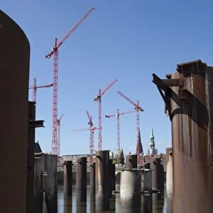 Steel pillars in the water in front of construction cranes in the new development area of HafenCity, Hamburg, Germany, Europe