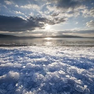 Sunlight with moody clouds, stacked ice floes on the shore of Reichenau Island, Baden-Wuerttemberg, Germany, Europe