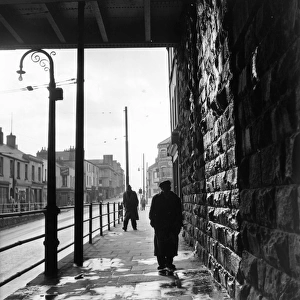 Tiger Bay; A man walking under a railway bridge in the dockland area of Cardiff