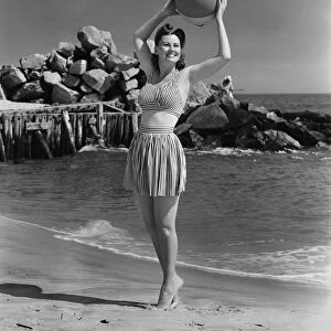 Woman holding ball on beach, (B&W)