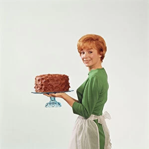 Woman holding cake, smiling, portrait