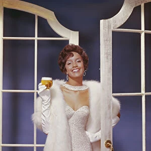 Young woman wearing fur jacket holding beer glass, smiling, portrait