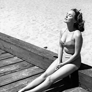 A young lady wearing a bikini and sandals sunbathing