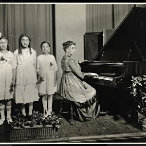 Woman playing the piano while three girls sing at the New York Association for the Blind