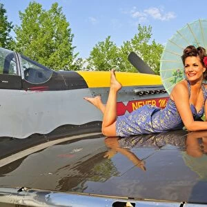 1940s style pin-up girl with parasol on a vintage P-51 Mustang