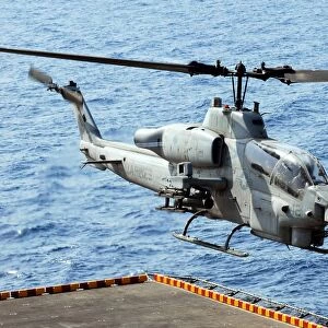An AH-1W Super Cobra helicopter launches off the flight deck of USS Peleliu