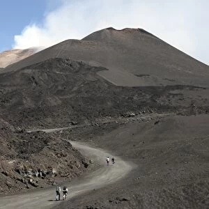 Hikers walking towards summit area of Mount Etna volcano, Sicily, Italy