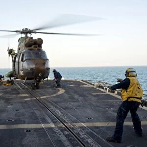 Sailors place chocks and chains on a French Army SA 380 Puma helicopter