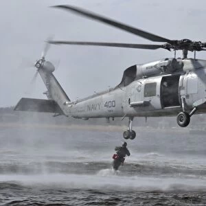 A search and rescue swimmer jumps from an SH-60F Sea Hawk helicopter
