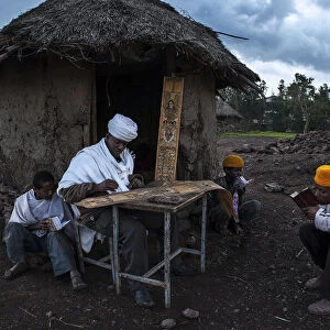 A priest is painting while some guys are praying (Lalibela - Ethiopia)