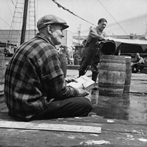 New England fisherman checking baskets of fish as they are lifted from his ship, New York, 1943. Creator: Gordon Parks
