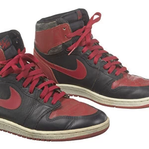 Pair of red and black Air Jordan I high top sneakers made by Nike, 1985. Creator: Nike