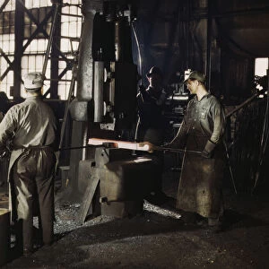 Working with a small steam drop hammer, blacksmith shop, Santa Fe RR shops, Topeka, Kansas, 1943. Creator: Jack Delano