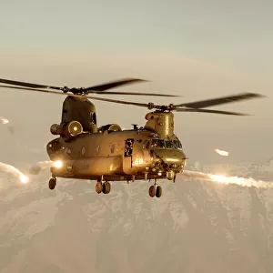 An RAF Chinook helicopter in silhouette, flying over Afghanistan