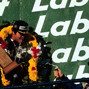 Alan Jones celebrates on the podium with Didier Pironi after winning