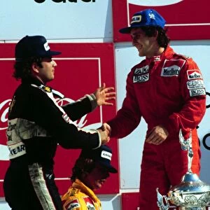 Elio de Angelis congratulates race winner Alain Prost on the podium