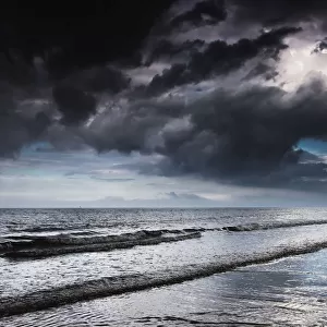 Dark storm clouds over the ocean with waves rolling into the shore; Druridge bay northumberland england