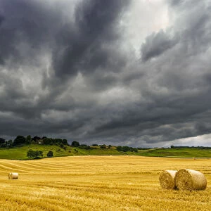 Dark Storm Clouds Roll Over A Golden Farm Field With Hay Bales; Ravensworth, North Yorkshire, England