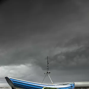 Rowboats sitting on trailers on the shore under storm clouds; Boulmer northumberland england