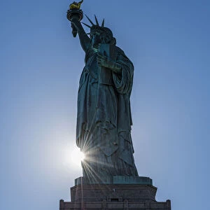 Sun Setting Behind The Statue Of Liberty, Liberty Island; New York City, New York, United States Of America