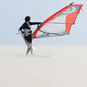 A Windsurfer Walks On The Sand Of Punta Paloma Beach With His Board; Tarifa, Cadiz, Andalusia, Spain