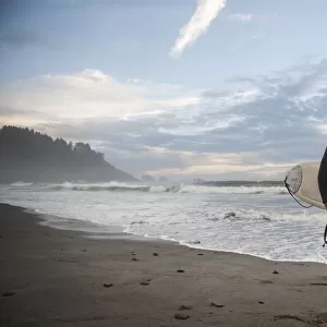 A Young Man Carries His Surfboard Down The Beach; La Push Washington United States Of America