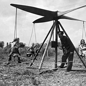 A airman operates a propeller roundabout. Seen here giving local children a ride