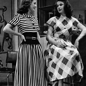 Audreywearing a brown and white striped dress. Rita in a big check pattern