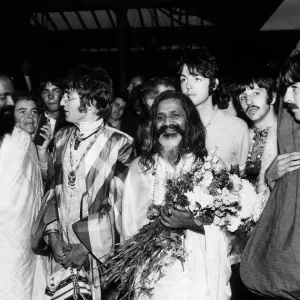 The Beatles with the Maharishi Mahesh Yogi who is clutching bundles of flowers Beatles