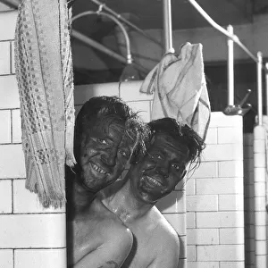 Coal miners John Derbyshire front and Vinc Higson give each other assistance to get clean